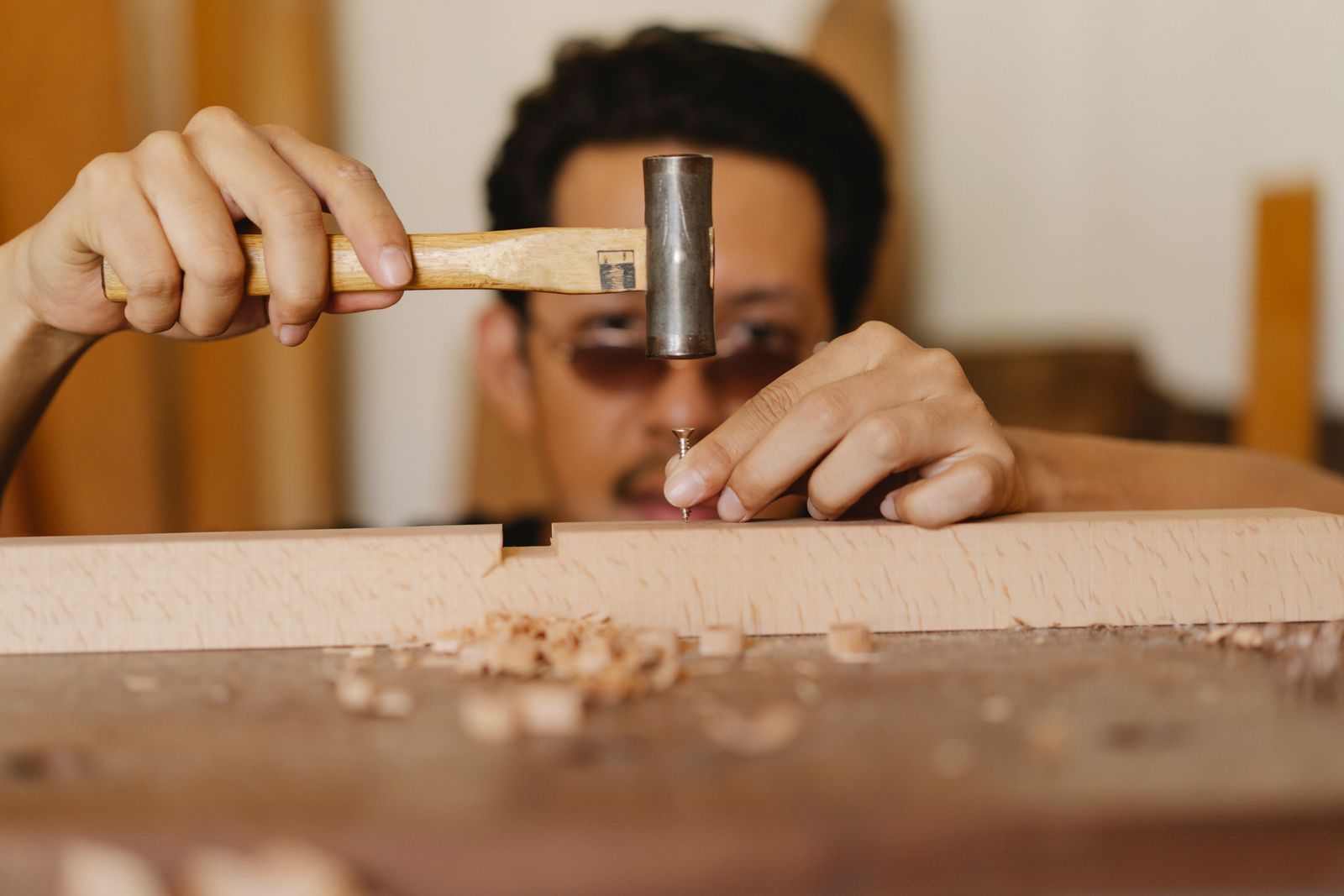 Carpenter nailing a wooden plank in the workshop