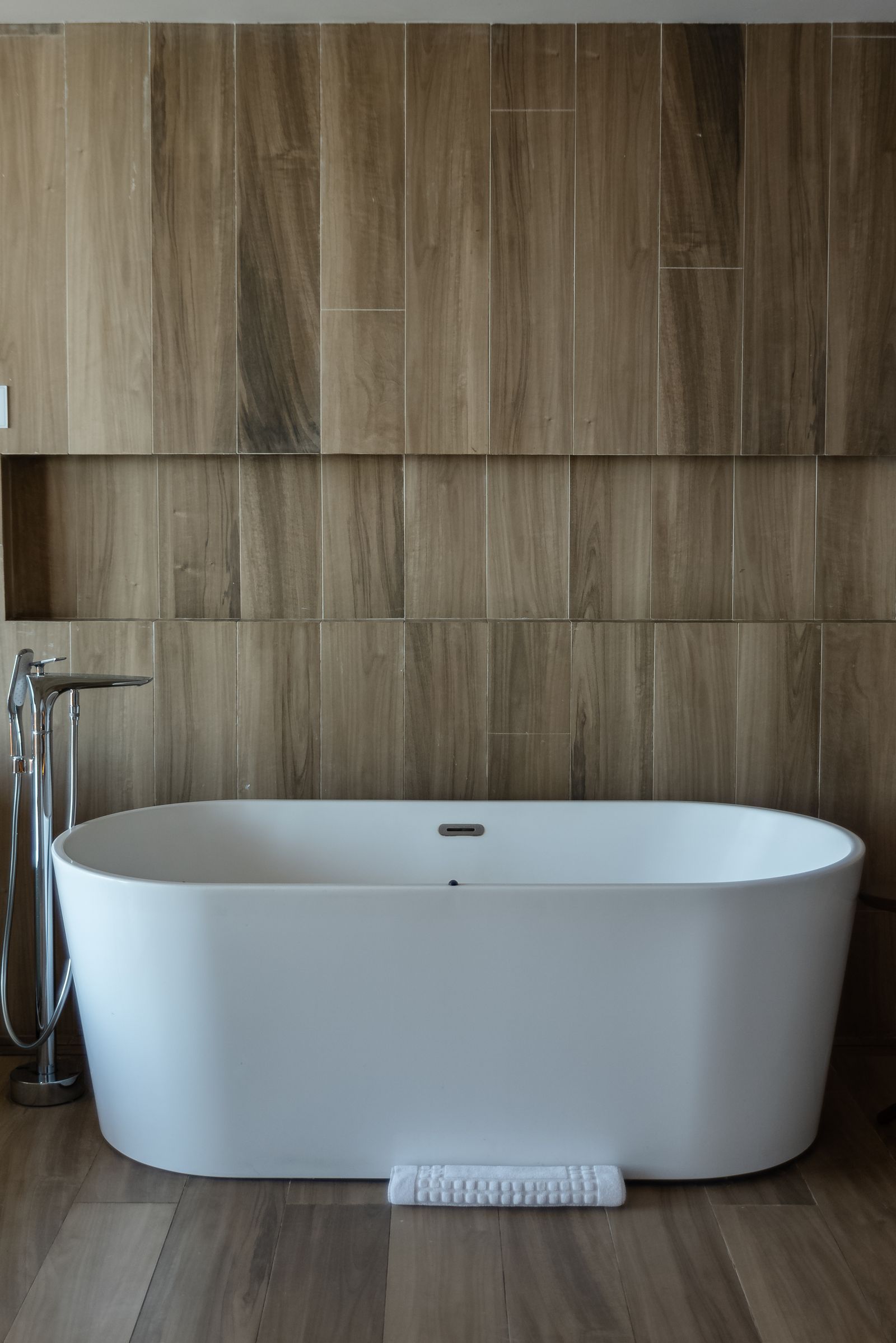 Freestanding white tub in a bathroom with wood accents